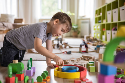 Side view of boy playing with toys at home