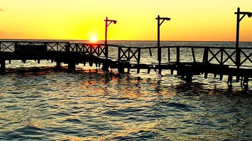 Silhouette pier over sea against sky during sunset