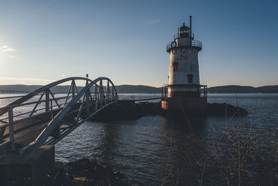 Lighthouse by sea against sky