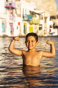 Shirtless boy flexing muscles in sea