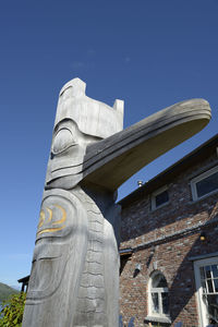 Low angle view of statue against building against sky