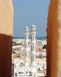 Buildings and mosque in city against sky