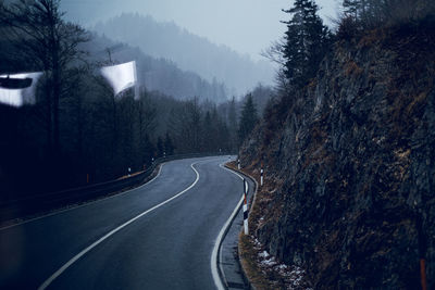 Empty road amidst trees against sky