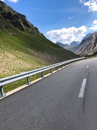 Road by mountains against sky