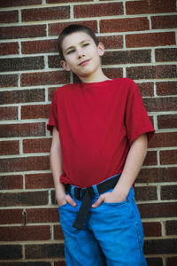 Portrait of teenage boy standing against brick wall