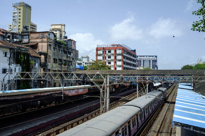 Train on railroad tracks in city against sky