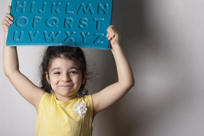 Portrait of smiling young woman standing against wall