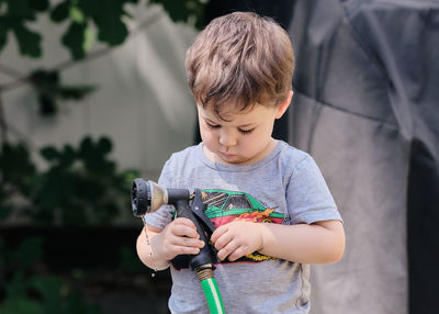 Curious toddler is playing with objects in the backyard.