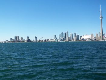 Sea and buildings against clear blue sky