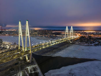 Illuminated bridge over river against sky at night