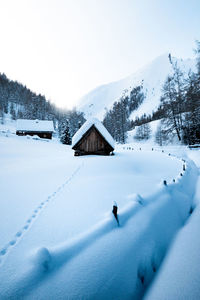 Snow covered landscape and houses against sky