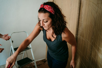 Young woman looking away while standing against wall