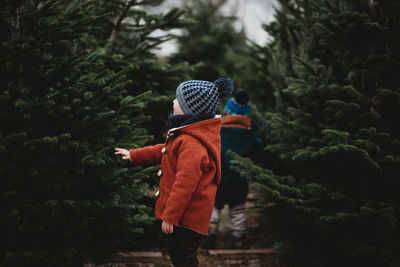 Boy in red wool coat touching a tree during christmas season