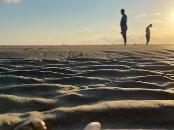 People walking on sand dune against sky