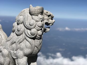 Close-up of angel statue against cloudy sky