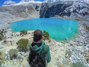 Rear view of man standing by lake against mountains