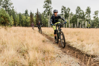 Friends riding mountain bikes on meadow trail