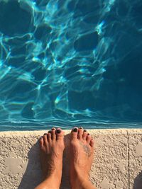 Low section of woman standing at poolside