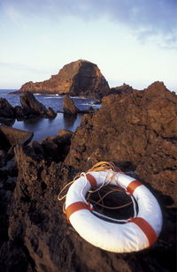 High angle view of life belt on rock formations by sea against sky