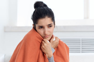 Ill woman looking away while sitting at home