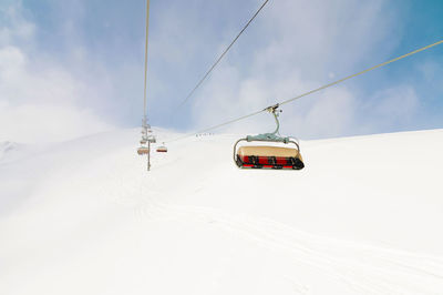 An open-air lift that goes to the top of the mountain for downhill skiing. sunny day surrounded by