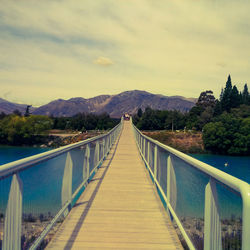 Footbridge over mountain against sky