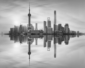 Reflection of skyscrapers in city against sky