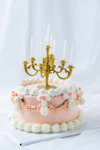 Light pink vintage butter cream cake with candle on white cloth background,