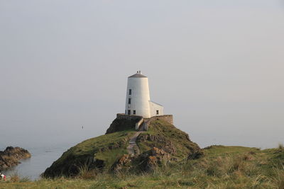 Lighthouse by sea against sky