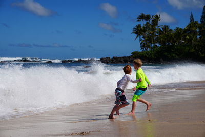 Young boy running from the waves on the beach in hawaii. 