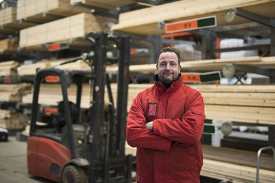 Portrait of confident salesman standing arms crossed in warehouse at hardware store