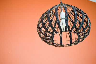 Low angle view of illuminated lamp against orange wall