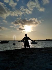 Silhouette man standing on beach against sky during sunset