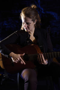 Woman playing guitar in darkroom