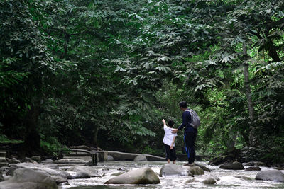 Young couple standing on rock in forest