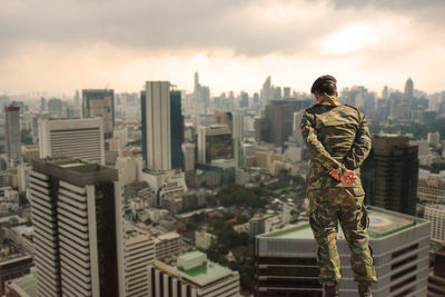 Rear view of woman standing against buildings in city