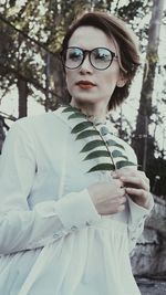 Portrait of young woman standing against tree