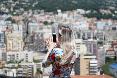 Midsection of woman photographing with city in background