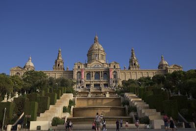Group of people in front of building against clear blue sky