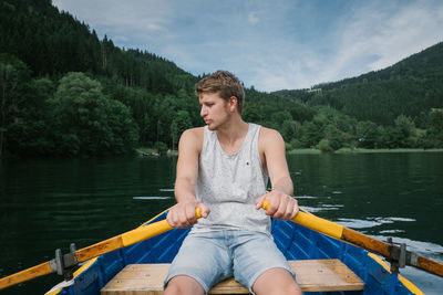 Man rowing boat in lake against trees