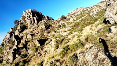 Low angle view of rocks on mountain against clear sky