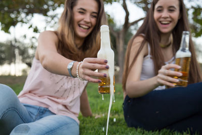 Happy friends holding beer bottles at park