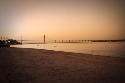 View of suspension bridge in city at sunset