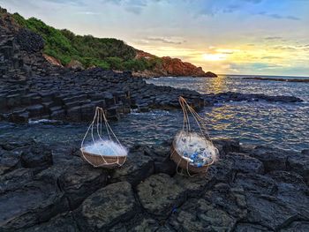 Scenic view of rocks at beach against sky during sunset