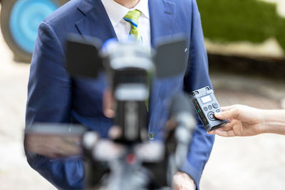 Midsection of man holding camera while standing outdoors