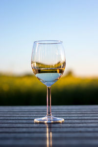 Close-up of wineglass on table against sky