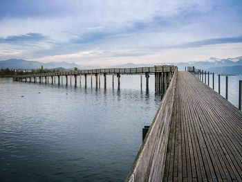 Wooden pier over river against sky