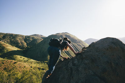 Rear view of man on rock against sky