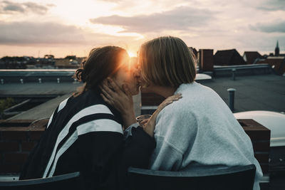 Rear view of couple sitting against sky during sunset