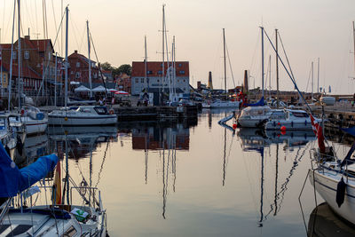 Boats moored in harbor at sunset